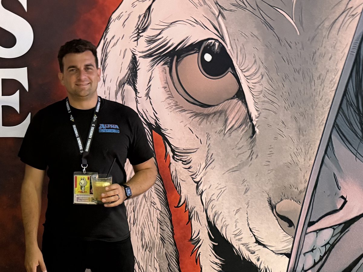 Orlando Salvatore at a convention, in front of a large comic-art banner, wearing an exhibitor badge.
